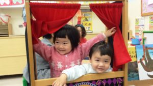 Two young children playing in puppet theater